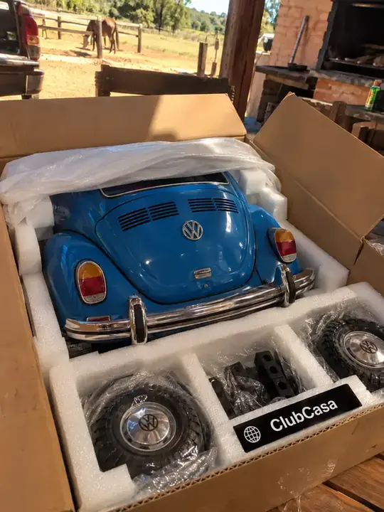 Cliente desembalando o ClubCasa com o Fusca azul na oficina rural