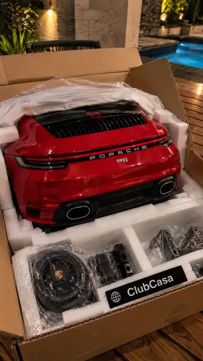 Miniatura do Porsche 911 desembalada no pátio ao lado do ClubCasa