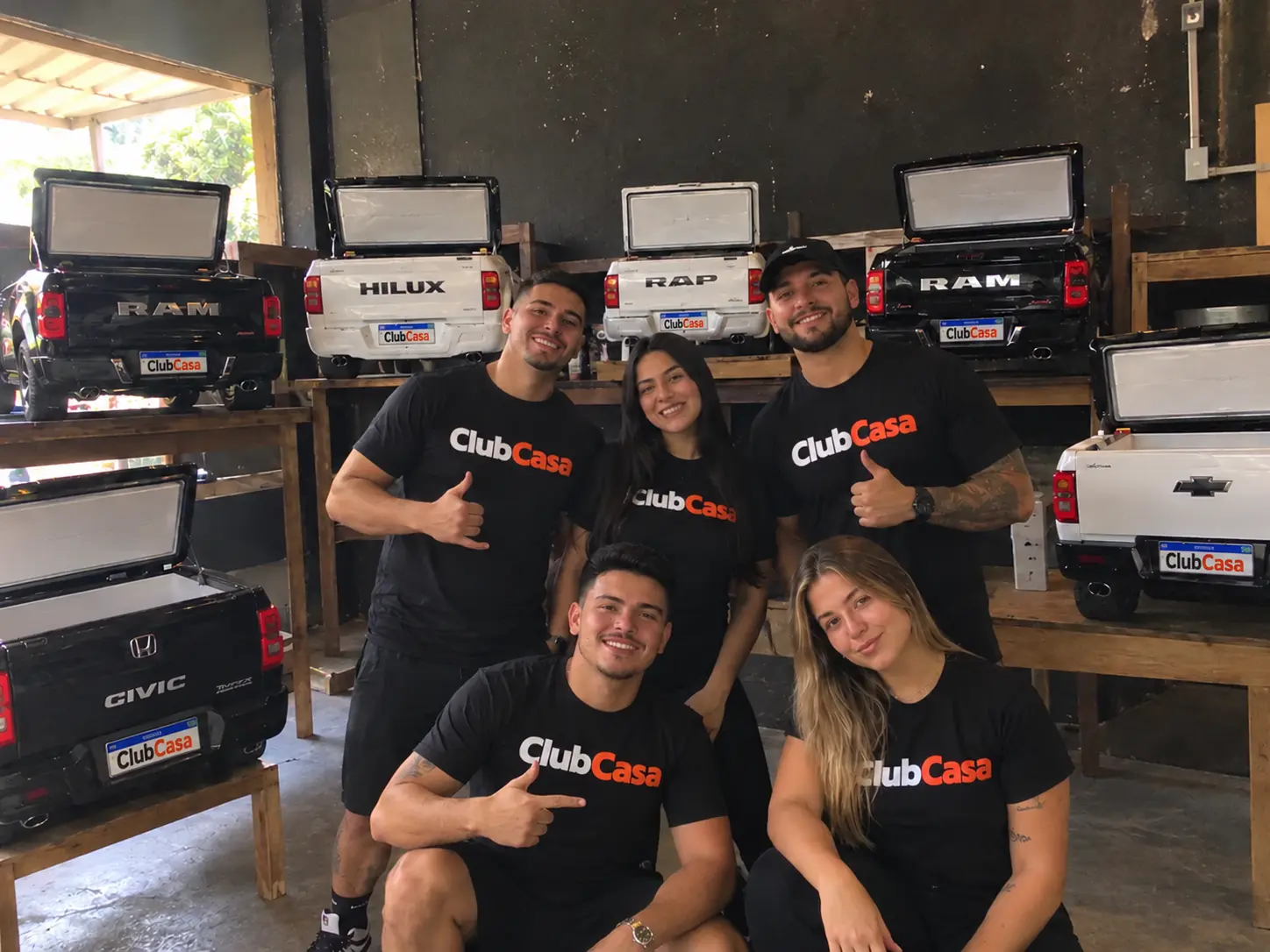 Equipe ClubCasa ao lado de coolers personalizados em formato de carro na oficina